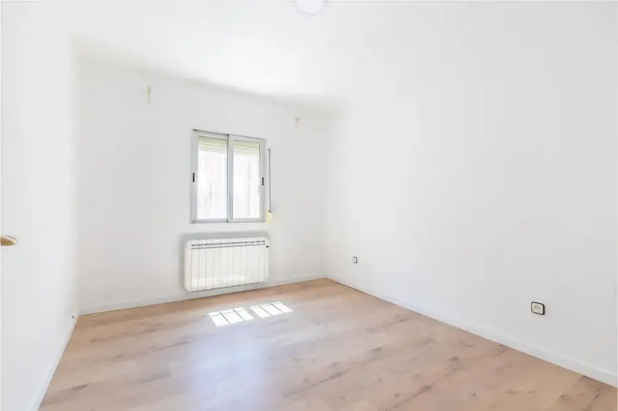 Habitación después: suelo nuevo, pintura neutra, radiador y más luz
