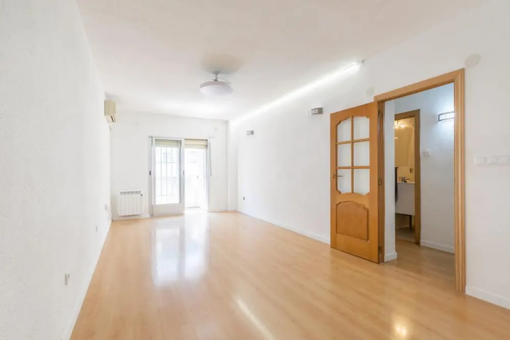 Salón después de la puesta a punto: paredes claras, suelo nuevo y más luz